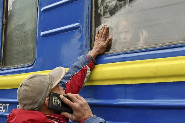 A child speaks on the phone as he says goodbye to a relative looking out the window of a train carriage waiting to leave Kramatorsk for western Ukraine at the railway station in Kramatorsk, eastern Ukraine, Wednesday, March 2, 2022. Roughly 874,000 people have fled Ukraine and the U.N. refugee agency warned the number could cross the 1 million mark soon. Countless others have taken shelter underground. (Photo by Andriy Andriyenko/AP Photo)