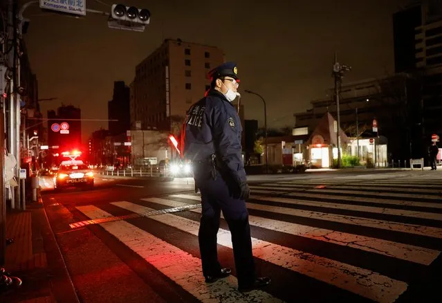 A police officer tries to control traffics on the street during an electric stoppage at the area after an earthquake in Tokyo, Japan on March 17, 2022. (Photo by Issei Kato/Reuters)