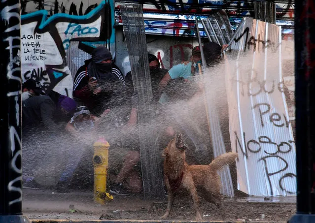 Demonstrators clash with riot police during a protest against the government's economic policies, in the surroundings of La Moneda presidential palace in Santiago, on November 5, 2019. Unrest began in Chile last October 18 with protests against a rise in transport tickets and other austerity measures and descended into vandalism, looting, and clashes between demonstrators and police. Protesters are angry about low salaries and pensions, poor public healthcare and education, and a yawning gap between rich and poor. (Photo by Martin Bernetti/ AFP Photo)