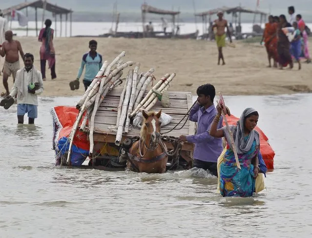 A shopkeeper uses a horse cart to transport his belongings from the flooded banks of river Ganga after heavy monsoon rains in the northern India caused the rise in water levels, in Allahabad, India, July 24, 2015. (Photo by Jitendra Prakash/Reuters)