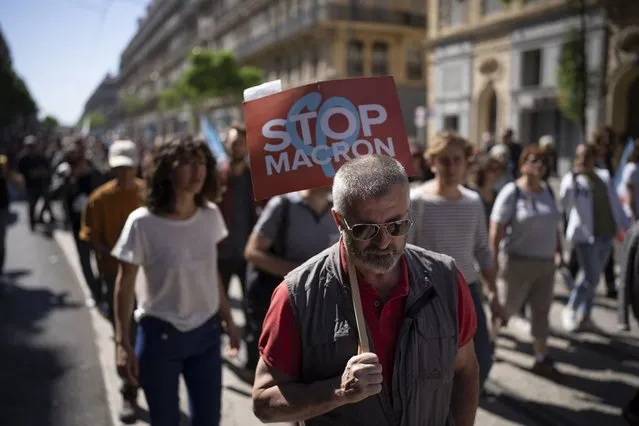 A protester holds a sign reading “Stop Macron” during a May Day demonstration in Marseille, southern France, Sunday, May 1, 2022. May 1 is celebrated as the International Labour Day or May Day across the world. (Photo by Daniel Cole/AP Photo)