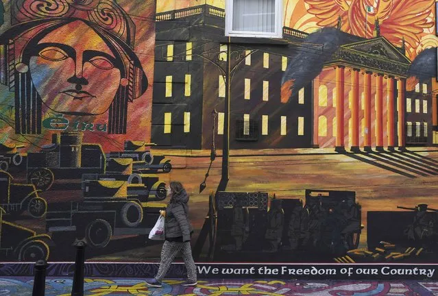 A woman walks past a political mural, which includes a representation of the Storming Parliament building, in the Falls Road area of west Belfast, Northern Ireland, February 28, 2017. (Photo by Toby Melville/Reuters)
