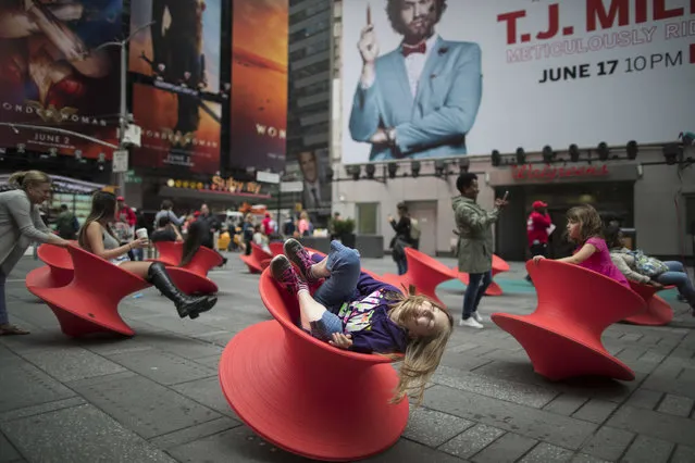 Taylor Goforth, center, and Brooklyn Richter, right, of Powell, Tenn., enjoy the spinning chairs while visiting New York's Times Square, Wednesday, May 31, 2017. (Photo by Mary Altaffer/AP Photo)