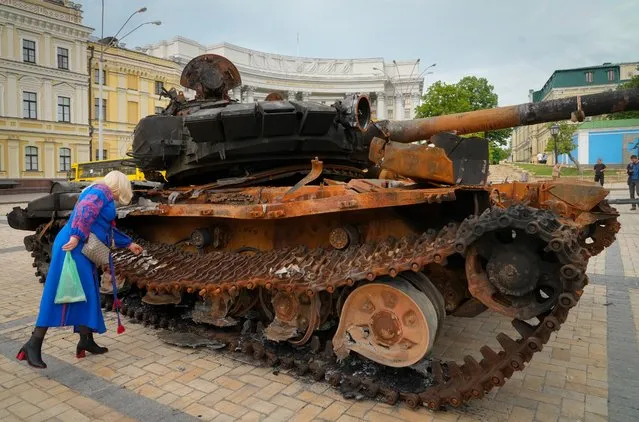 A woman looks at a destroyed Russian tank installed as a symbol of war in central Kyiv, Ukraine, Friday, May 20, 2022. (Photo by Efrem Lukatsky/AP Photo)