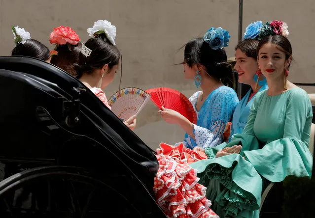 Women wearing traditional sevillana dresses use fans to cool off as they sit on a horse-drawn carriage during an episode of exceptionally high temperatures for the time of year in Cordoba, Spain on May 21, 2022. (Photo by Jon Nazca/Reuters)