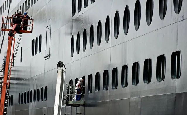 Workers paint and clean the ocean liner Queen Mary II in a dock at Blohm&Voss shipyard in Hamburg, Germany, June 14, 2016. (Photo by Fabian Bimmer/Reuters)