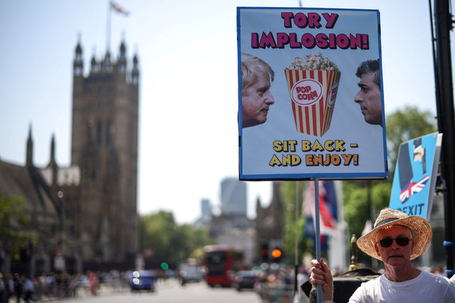 A protestor holds a placard caricaturing the relationship and the political situation between Britain's Prime Minister Rishi Sunak and his predecessor Boris Jonson, during a protest rally outside Palace of Westminster, home of the Houses of Parliament, in Westminster, central London, on June 14, 2023. British Prime Minister Rishi Sunak on June 12, 2023 became embroiled in a public war of words with Boris Johnson, in a spat over the former leader's controversial awards to his key political allies. (Photo by Henry Nicholls/AFP Photo)