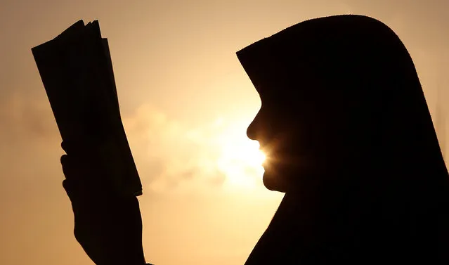 A Palestinian girl reads the Quran, Islam's holy book, at sunset in Gaza City on Friday, July 4, 2014. Muslims throughout the world are celebrating the holy fasting month of Ramadan, refraining from eating, drinking, and smoking from dawn to dusk. (Photo by Hatem Moussa/AP Photo)