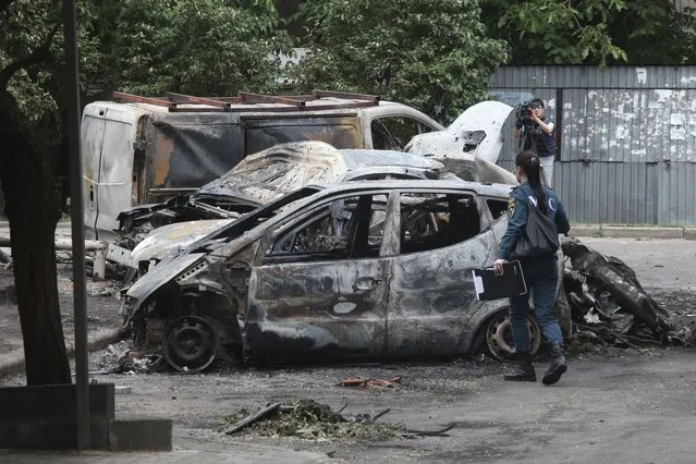 A Donetsk People Republic Emergency Situations Ministry employee walks at the scene of burned vehicles after the shelling in the Petrovsky district of Donetsk, on the territory which is under the Government of the Donetsk People's Republic control, eastern Ukraine, Sunday, June 5, 2022. The Russian State news agency TASS said five civilians were killed and 20 were injured Saturday as a result of multiple explosions close to the city of Donetsk. (Photo by AP Photo/Stringer)