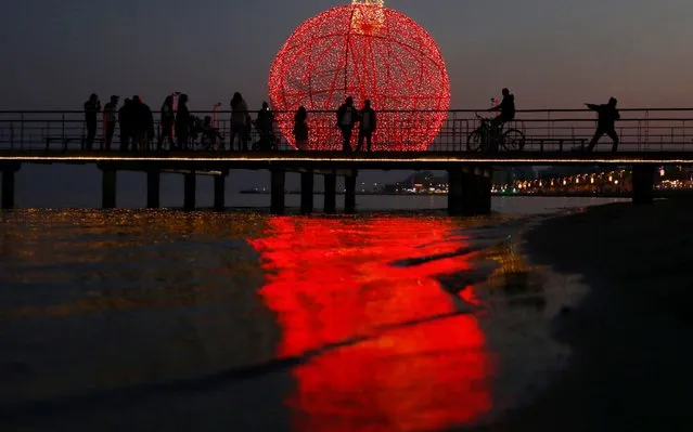 People are seen on a pier in front of a giant illuminated Christmas ball in Larnaca, Cyprus on December 22, 2019. (Photo by Yiannis Kourtoglou/Reuters)