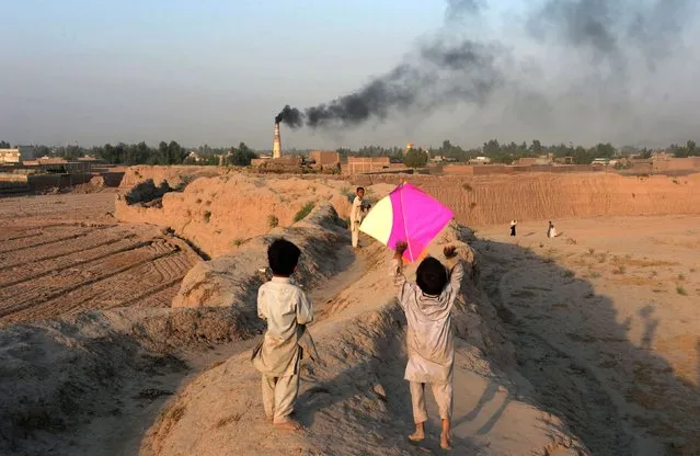 This photograph taken on October 18, 2016 shows Afghan youths playing with a kite on the outskirts of Jalalabad. (Photo by Noorullah Shirzada/AFP Photo)
