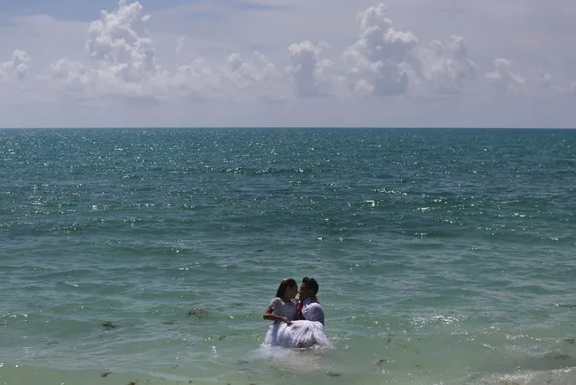 A wedding couple poses in the sea during a photo session on Isla Blanca beach in Cancun, Mexico, August 11, 2015. (Photo by Edgard Garrido/Reuters)