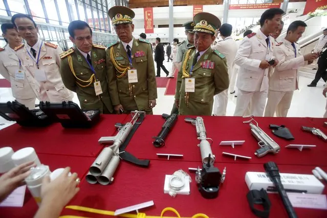 Laotian police officers (in green uniforms) look at Vietnamese-made weapons on display during celebrations to commemorate the 70th anniversary of the establishment of the Vietnam Public Security police force at the National Convention Center in Hanoi August 18, 2015. (Photo by Reuters/Kham)