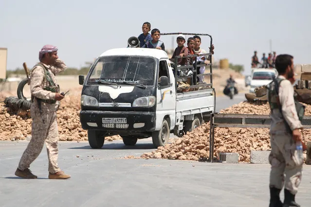 Syria Democratic Forces (SDF) fighters man a checkpoint as civilians on pick-up trucks evacuate from the southern districts of Manbij city after the SDF advanced into it in Aleppo Governorate, Syria, July 1, 2016. (Photo by Rodi Said/Reuters)