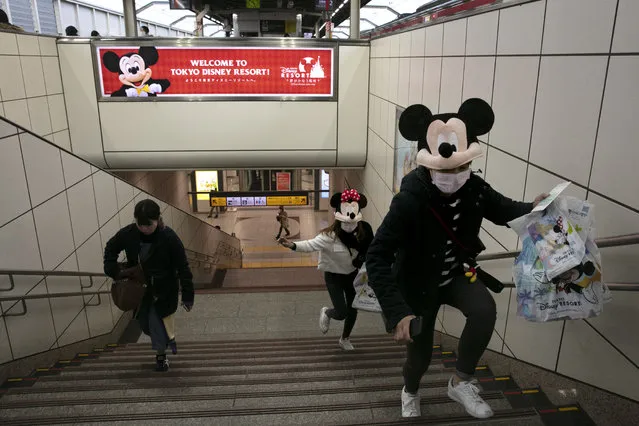 Two women rush to catch a train after visiting Tokyo Disneyland in Urayasu, near Tokyo, Friday, February 28, 2020. The amusement park will be closed from Saturday until March 15 in an effort to prevent the spread of COVID-19. (Photo by Jae C. Hong/AP Photo)