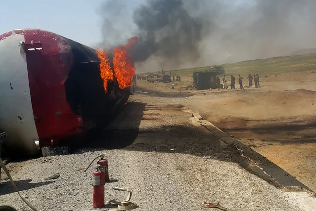 In this photograph taken on May 8, 2016, Afghan bystanders inspect the site of a traffic accident in Ghazni province on the main Kabul-Kandahar Highway. At least 73 people were killed on May 8, 2016, when two passenger buses and an oil tanker burst into flames in a head-on collision in eastern Afghanistan, health officials said, in one of the worst road accidents in the war-battered nation. Bloodied, dazed and badly burned, many of the survivors streamed into Ghazni's main provincial hospital, while many others were rushed in ambulances to health facilities in southern Kandahar city. (Photo by AFP Photo/Stringer)