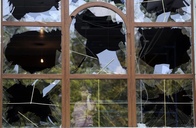 A woman looks out from a damaged window following what locals say was shelling by Ukrainian forces in Donetsk August 7, 2014. The Ukrainian government said on Thursday it was suspending a ceasefire with separatist rebels at the crash site of the Malaysian airliner after an international recovery mission had been halted. (Photo by Sergei Karpukhin/Reuters)