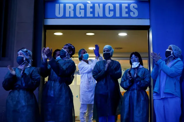 Health workers react as neighbors of the Dos de Mayo Hospital take part in the nationwide daily gratitude applause in Barcelona, Spain, 30 March 2020. Spain is on its 16th consecutive day of national lockdown imposed by the government in an attempt to slow down the spread of the pandemic COVID-19 disease caused by the SARS-CoV-2 coronavirus. (Photo by Quique García/EPA/EFE)