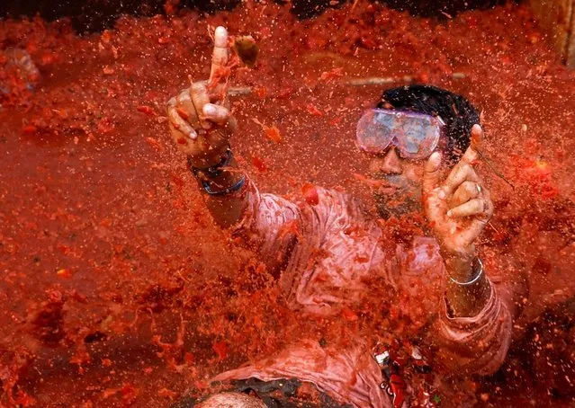 Revelers play in tomato pulp during the annual “La Tomatina” food fight festival in Bunol, Spain on August 31, 2022. (Photo by Juan Medina/Reuters)