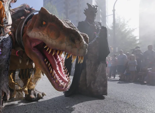 A character leading a dinosaur during the Dragon Con science fiction and fantasy parade in Atlanta, Georgia, USA, 30 August 2014. Thousands of people crowded downtown to watch the 28th annual science fiction and fantasy convention in Atlanta. (Photo by Erik S. Lesser/EPA)