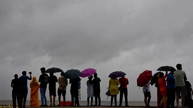 Dark clouds loom over the Bay of Bengal as local people and tourists stand along a beach in Digha, around 200km southwest of Kolkata, on October 24, 2024, as cyclone Dana is likely to hit the coasts of India's West Bengal and Odisha states. At least 1.1 million people on India's eastern coast are fleeing to storm shelters inland, hours before a powerful cyclone is expected to hammer the low-lying region, ministers said on October 24. (Photo by Dibyangshu Sarkar/AFP Photo)