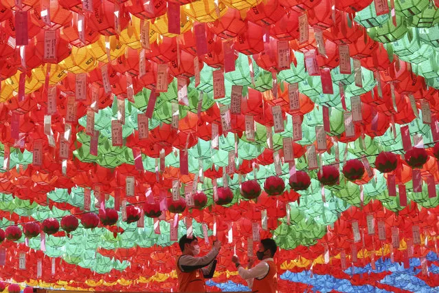 Workers wearing face masks to help protect against the spread of the new coronavirus attach name tags of Buddhists who made donation to lanterns to celebrate Buddha's birthday at the Chogyesa temple in Seoul, South Korea, Thursday, April 30, 2020. (Photo by Ahn Young-joon/AP Photo)