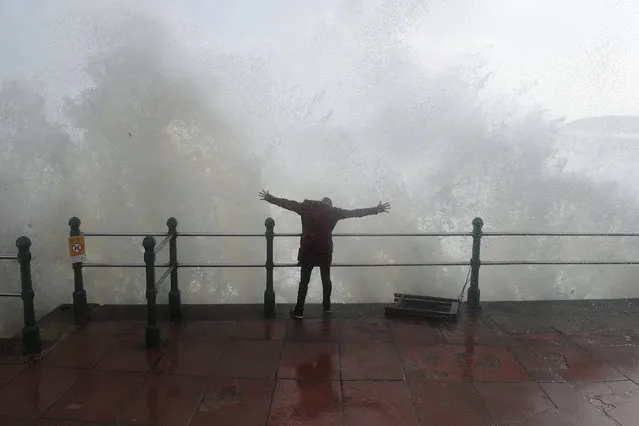 A woman stands as waves crash against the sea wall at Penzanze, Cornwall southwestern England, as the remnants of  Hurricane Ophelia begins to hit parts of Britain and Ireland. Ireland's meteorological service is predicting wind gusts of 120 kph to 150 kph (75 mph to 93 mph), sparking fears of travel chaos. Some flights have been cancelled, and aviation officials are warning travelers to check the latest information before going to the airport Monday. (Photo by Ben Birchall/PA Wire via AP Photo)