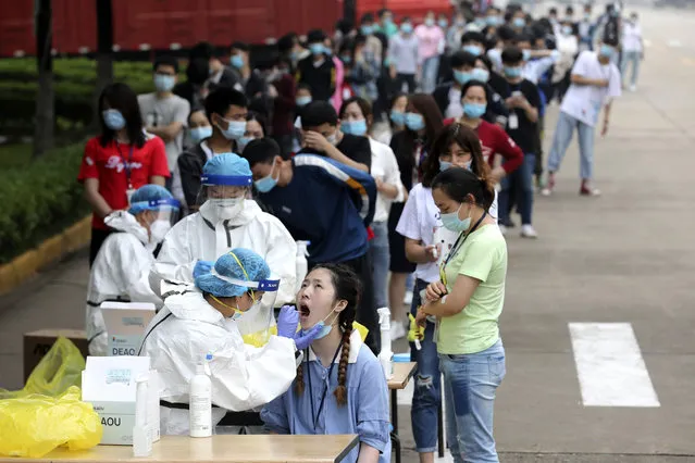 Workers line up for medical workers to take swabs for the coronavirus test at a large factory in Wuhan in central China's Hubei province Friday, May 15, 2020. Wuhan have begun testing inhabitants for the coronavirus as a program to test everyone in the Chinese city of 11 million people in 10 days got underway. (Photo by Chinatopix via AP Photo)