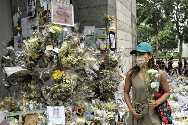 A woman lays flowers as a tribute outside the British Consulate in Hong Kong, Friday, September 16, 2022. In Britain, Thousands of mourners waited for hours Thursday in a line that stretched for almost 5 miles (8 kilometers) across London for the chance to spend a few minutes filing past Queen Elizabeth II's coffin while she lies in state. (Photo by Anthony Kwan/AP Photo)