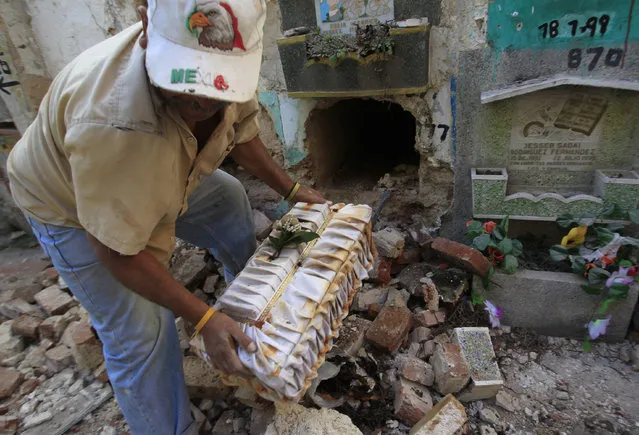 A grave cleaner takes the coffin of a child out of a crypt during exhumation works at the children's section of the Cemetery General in Guatemala City November 27, 2012. (Photo by Jorge Dan Lopez/Reuters)