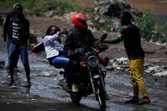 Opposition supporters try to stop a man and a woman on a motorbike to check their fingers for ink as to know if they voted in the re-run presidential election, in the slum area of Mathare in Nairobi, Kenya on October 26, 2017. (Photo by Siegfried Modola/Reuters)