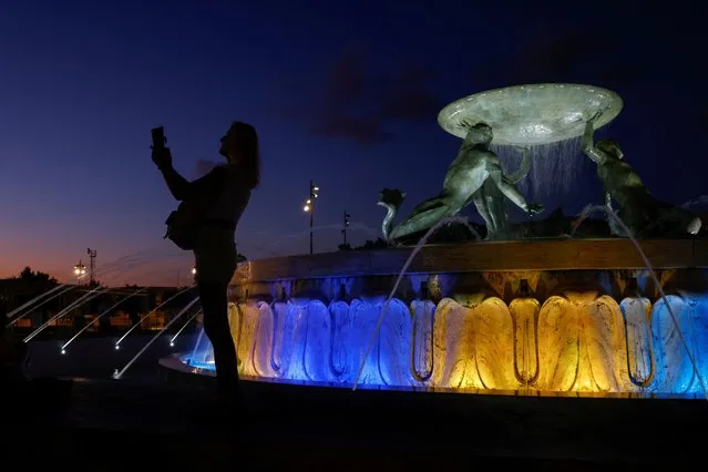 The Triton Fountain is lit in Ukrainian colours, as Ukrainians in Malta take part in a demonstration ahead of Ukraine's Independence Day and six months since the Russian invasion began, in Valletta, Malta on August 23, 2022. (Photo by Darrin Zammit Lupi/Reuters)
