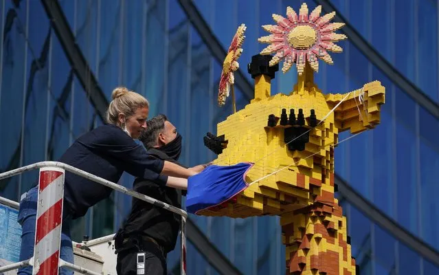 Workers don a protective face mask on a seven-meter-tall giraffe made of 45,000 Lego pieces prior to the reopening of the Legoland Discovery Centre during the novel coronavirus pandemic on June 09, 2020 in Berlin, Germany. Most restrictions on public life that had been imposed by authorities in March to stem the spread of the virus have lifted. The outlook for an economic recovery remains, however, uncertain, as many businesses report sluggish sales volume. (Photo by Sean Gallup/Getty Images)