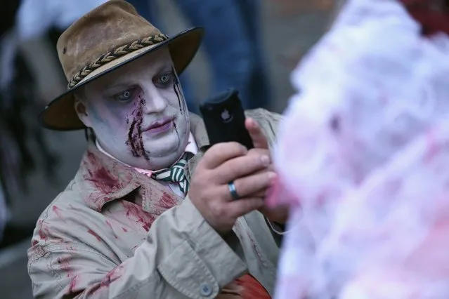 A zombie enthiusiast photographs his bride before setting out on a “Zombie Walk” in the city center on October 27, 2012 in Berlin, Germany. Approximately 150 zombies, who had organized themselves through Facebook, walked and limped across Alexanderplatz, growled and moaned at passersby and performed their jerking dances. (Photo by Sean Gallup)