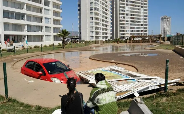 A couple look at a car inside a pool after an earthquake hit areas of central Chile, in Coquimbo city, north of Santiago, Chile, September 17, 2015. (Photo by Mauricio Ubilla/Reuters)