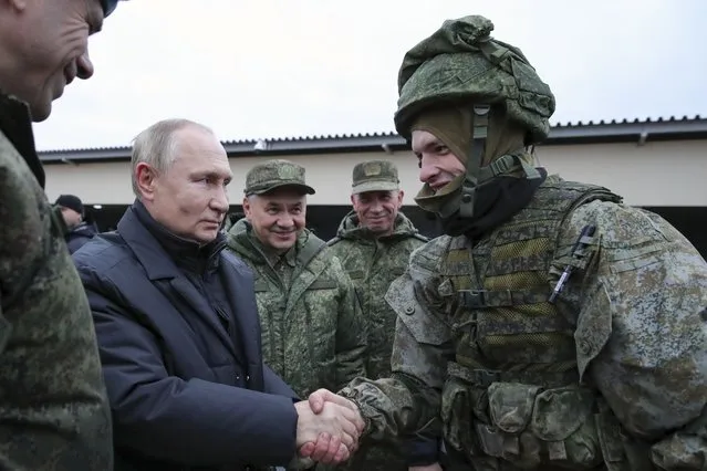 Russian President Vladimir Putin shakes hands with a soldier as he visits a military training centre of the Western Military District for mobilised reservists as Russian Defense Minister Sergei Shoigu, center, smiles in Ryazan Region, Russia, Thursday, October 20, 2022. The mobilized reservists that Russian President Vladimir Putin visited last week at a firing range southeast of Moscow looked picture-perfect. (Photo by Mikhail Klimentyev, Sputnik, Kremlin Pool Photo via AP Photo)