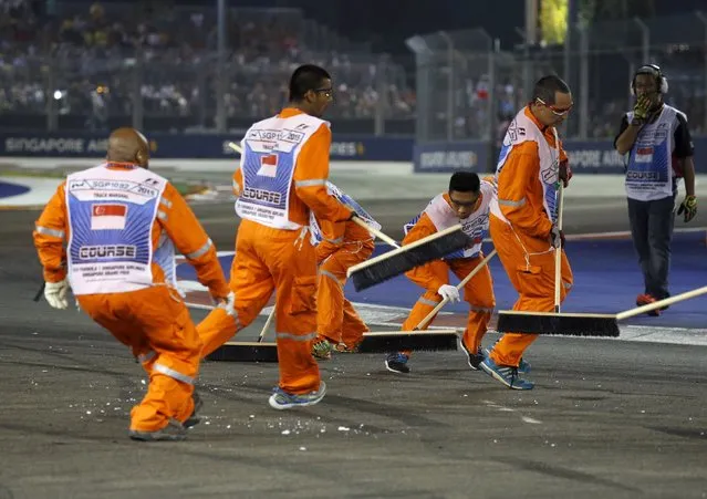 Track marshals sweep debris from the track after Force India Formula One driver Nico Hulkenberg of Germany crashed during the Singapore F1 Grand Prix at the Marina Bay street circuit September 20, 2015. (Photo by Edgar Su/Reuters)