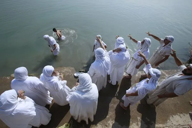 Followers of the ancient Sabean Mandaean religious sect pray alongside the Tigris river during the Prosperity Day celebration in the Tigris River in central Baghdad, Iraq, Tuesday, November 1, 2022. Mandaeism follows the teachings of John the Baptist, a saint in both the Christian and Islamic traditions, and its rites revolve around water and prosperity. (Photo by Hadi Mizban/AP Photo)