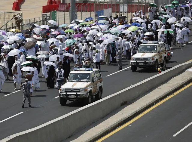 Police vehicles drive past pilgrims on a road in Mina, near the holy city of Mecca September 24, 2015. (Photo by Ahmad Masood/Reuters)
