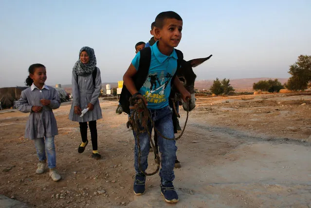 Palestinian students walk while others ride a donkey to school in the West Bank village of Sosiya, south of Hebron September 1, 2016. (Photo by Mussa Qawasma/Reuters)