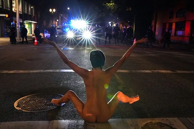 A nude protester faces off against Federal law enforcement officers, deployed under the Trump administration's new executive order to protect federal monuments and buildings, during a protest against racial inequality in Portland, Oregon, U.S. July 18, 2020. (Photo by Nathan Howard/Reuters)