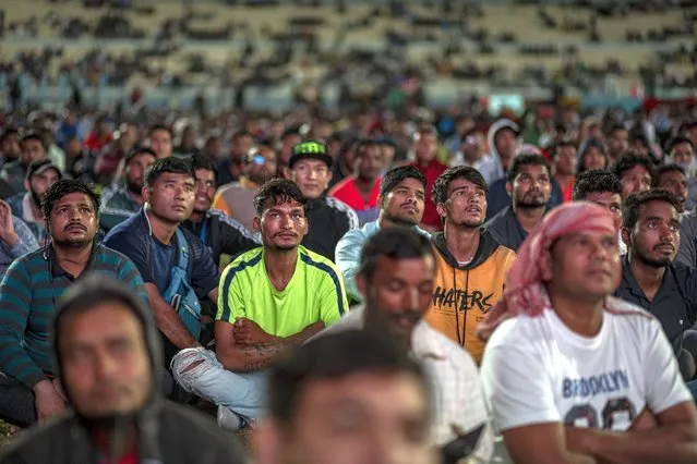 People, among them migrant workers, watch the FIFA World Cup Qatar 2022 match between England and Iran at the free-entry Industrial Area Fan Zone in the Asian Town Cricket Stadium, in Doha, Qatar, 21 November 2022. (Photo by Martin Divisek/EPA/EFE)