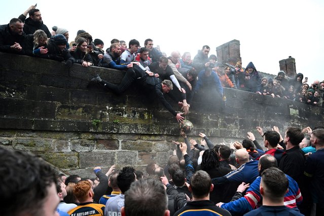 Competitors from the opposing teams, the Up'ards and the Down'ards, fight for the ball during the annual Royal Shrovetide Football Match in Ashbourne, northern England, on February 13, 2024. The mass-participation ball game involves two teams, whose players are defined by which side of a small brook that bisects the town they were born, aiming to score a goal, which are some three miles apart. The game, which has very few rules, is played over two 8 hour periods on Shrove Tuesday and Ash Wednesday. Royal Shrovetide Football is believed to have been played annually in Ashbourne since 1667. (Photo by Paul Ellis/AFP Photo)