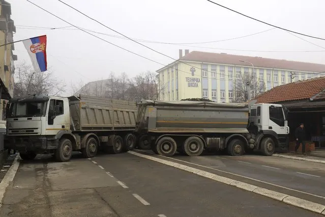 A man passes by a barricade made of trucks loaded with stones that was erected during the night on a street in northern, Serb-dominated part of ethnically divided town of Mitrovica, Kosovo, Tuesday, December 27, 2022. Serbia on Monday placed its security troops on the border with Kosovo on “the full state of combat readiness”, ignoring NATO's calls for calming down of tensions between the two wartime Balkan foes. (Photo by Bojan Slavkovic/AP Photo)