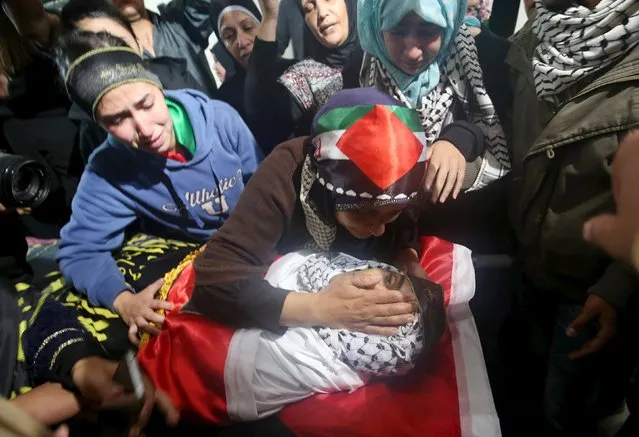 The mother of Palestinian man Mohnad Halabi, who was killed after stabbing and killing an off-duty Israeli soldier and a rabbi in Jerusalem's Old City on Saturday, touches his body during his funeral near the West Bank city of Ramallah October 9, 2015. (Photo by Mohamad Torokman/Reuters)