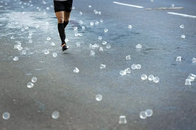 A runner passes empty cups near a refueling point during the annual Caracas Marathon in Caracas, Venezuela, Sunday, December 11, 2022. The race has the distances of 42K and 21K. (Photo by Matias Delacroix/AP Photo)