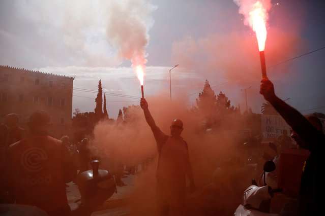 Protesters hold flares as they protest in front of the parliament building during a rally organized by the Communist-affiliated trade union PAME participating in the 24-hour nationwide strike in Athens, Greece, 17 April 2024. A 24-hour nationwide strike has been called by the private sector General Confederation of Employees of Greece (GSEE) demanding pay increases, formulation of collective labor agreements and action against the high prices of products. (Photo by Yannis Kolesidis/EPA/EFE)