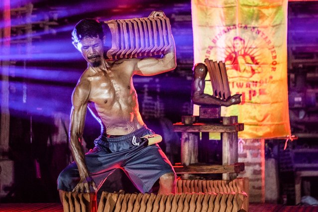 This photo taken on August 11, 2025 shows a roof tile factory worker posing while holding tiles during a traditional bodybuilding competition at a roof tile factory in Jatiwangi, West Java. This is a bodybuilding battle of a different kind – one where competitors are roof tile factory workers who pump clay instead of iron to bring attention to their dwindling trade. In Java's Jatiwangi city, an Indonesian hub for clay roof tile production nearly 200 kilometres from capital Jakarta, dozens of men have been lathering on oil to pose for crowds since 2015 to show they are not going anywhere. (Photo by Aditya Irawan/AFP Photo)