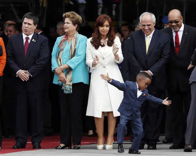 In this December 5, 2014 file photo, a youth performs at the inauguration of the new UNASUR headquarters building as Argentina's President Cristina Fernandez, center, UNASUR General secretary Ernesto Samper, second from right, and Suriname's President Desi Bouterse, right, watch in Quito, Ecuador. At left are Paraguay's President Horacio Cartes and Brazil's President Dilma Rousseff. (Photo by Dolores Ochoa/AP Photo)