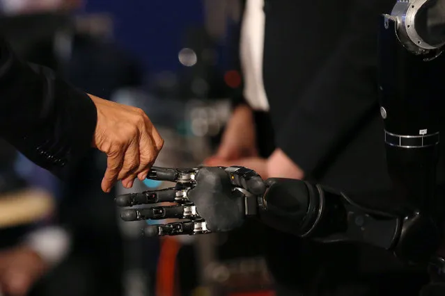 U.S. President Barack Obama touches a robotic arm operated by Nathan Copeland, a quadriplegic brain implant patient who can experience the sensation of touch and control a remote robotic arm with his brain during a tour of the innovation projects at the White House Frontiers conference in Pittsburgh, U.S. October 13, 2016. (Photo by Carlos Barria/Reuters)